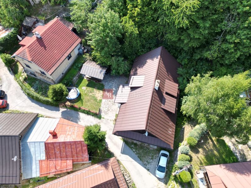 An aerial view of a cottage in Špania Dolina near Banská Bystrica surrounded by greenery and houses.