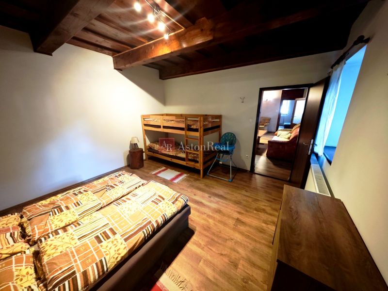 A room in a cabin with a bunk bed, a wooden decor floor, and ceiling beams.
