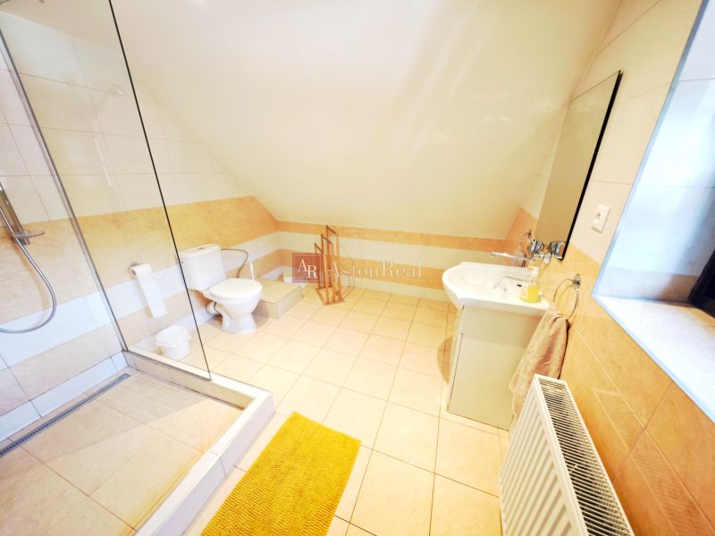 A bright bathroom in a cottage with a bathtub and a sink, complemented by light tiles.