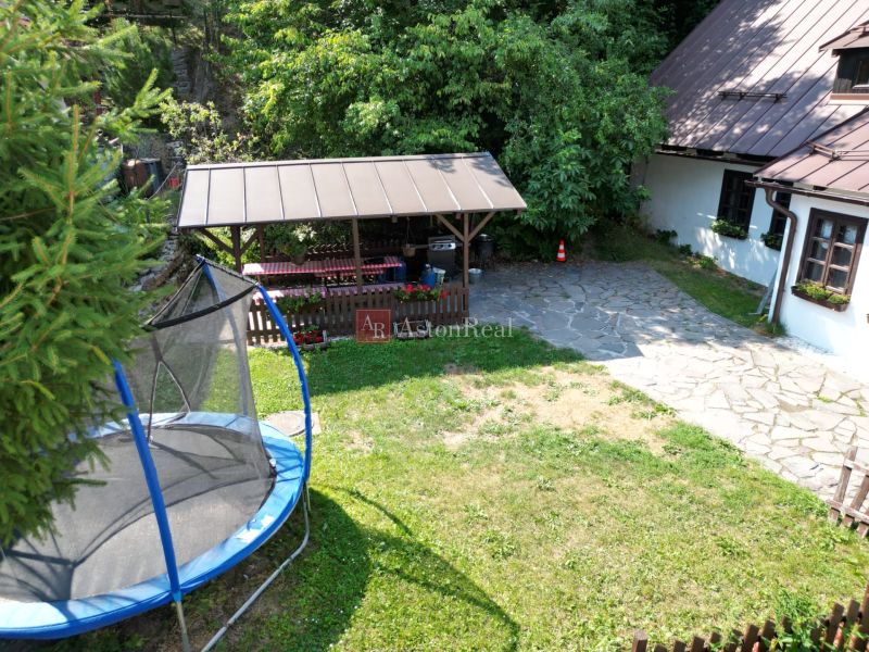 A yard of a cottage on Špania Dolina street in Banská Bystrica with a trampoline and a gazebo.