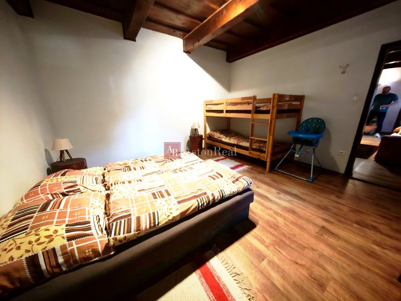A bedroom in a cabin with a double bed, a bunk bed, and a floor with a wooden decor.