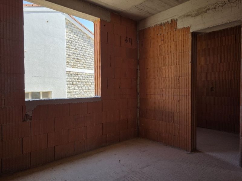 An unfinished building interior with brick walls and a window opening, without flooring.