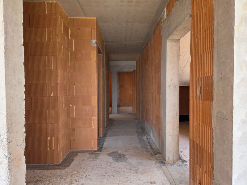 Shell construction of a 4-room apartment with brick walls and a concrete ceiling.