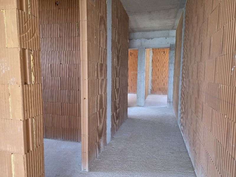 Interior of a 4-room apartment with bare brick walls and a cement floor.