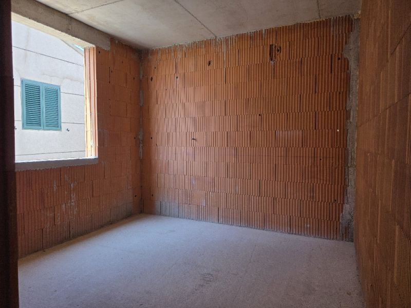 Unfinished room with brick walls, part of a 4-room apartment.