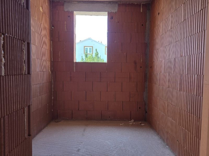 Red brick walls prepared for a 4-room apartment, with a view of the surrounding houses.