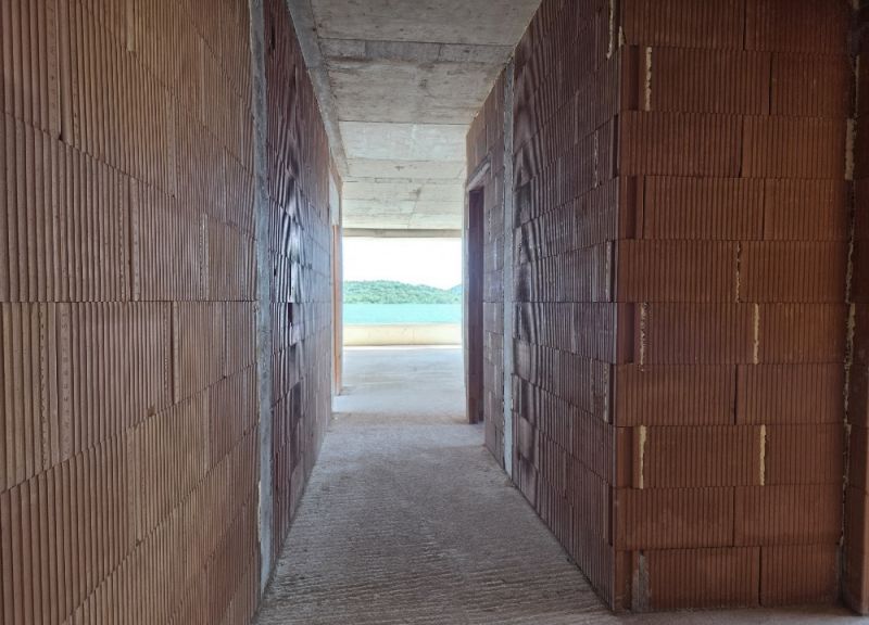 A hallway in a 4-room apartment with unplastered brick walls and a view into the distance.