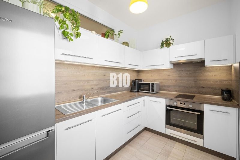 A kitchen in a 2-room apartment with white cabinets and wood decor.