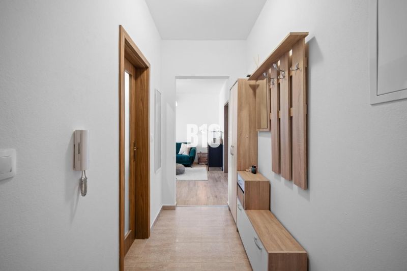 A hallway in a 2-room apartment with furniture and entrance to the living area.