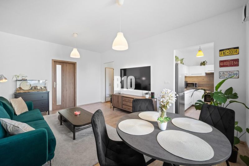 Living room in a two-room apartment with a wooden decor floor and a dining table.
