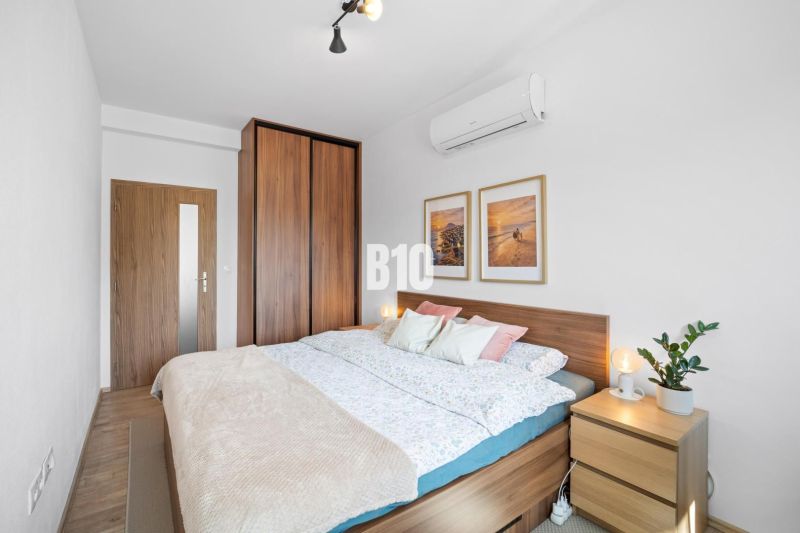 A bedroom with a bed, a dresser, and a floor with a wood decor in a two-room apartment.