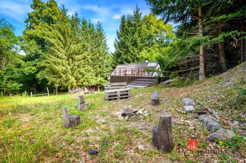 A cottage in Píla surrounded by forest with a seating area and a fire pit in the garden.