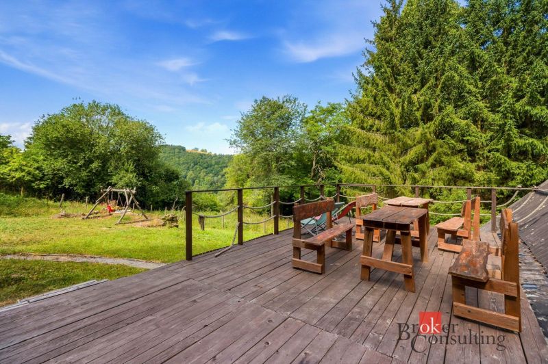 A cottage in Píla with a wooden terrace, wooden furniture, and a view of the trees and a swing.