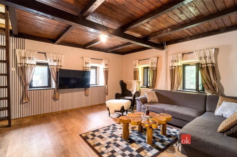 A living room in a cottage with a wooden decor floor and comfortable seating.