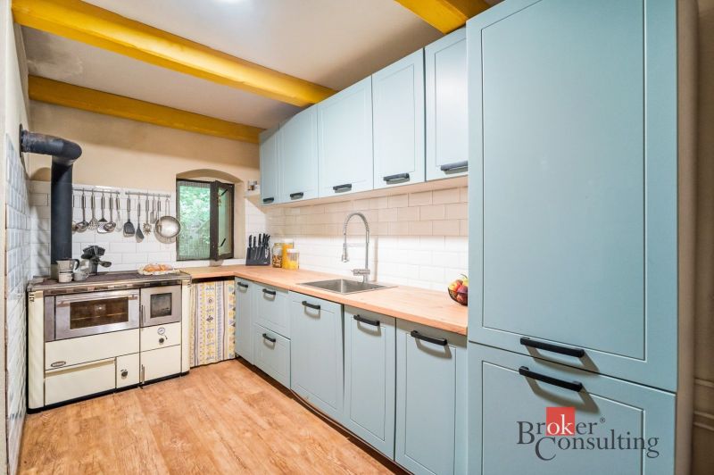 Rustic kitchen in a cottage with a wood-patterned floor and a traditional stove.