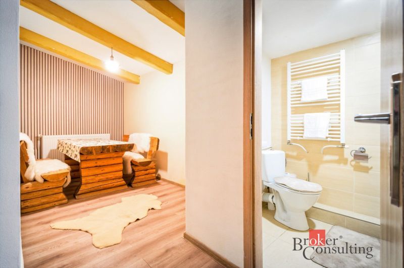 A cottage with wooden furniture and a floor with a wooden decor, next to a bathroom.