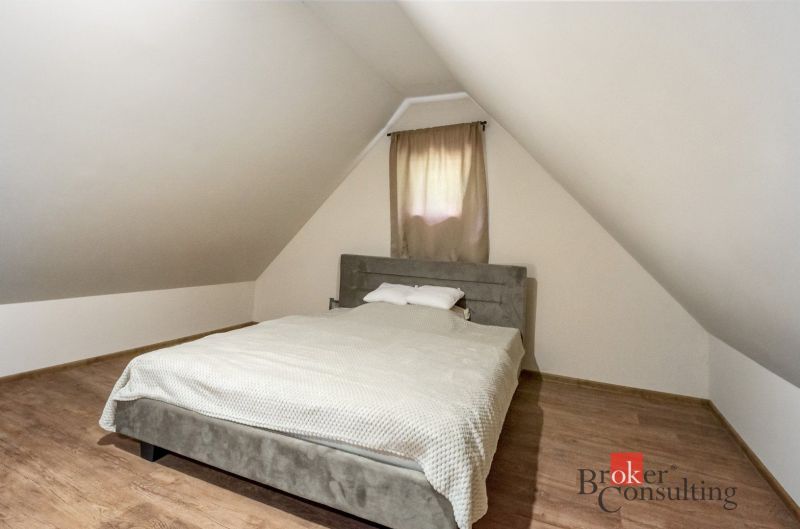 Attic bedroom in a cottage with a bed and a wooden decor floor.