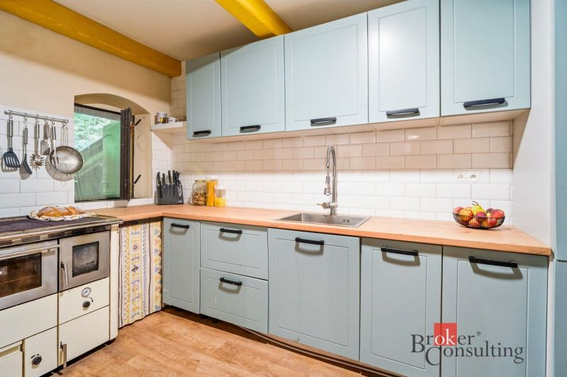 A kitchen in a cottage with blue cabinets, white tiles, and a wood-patterned floor.