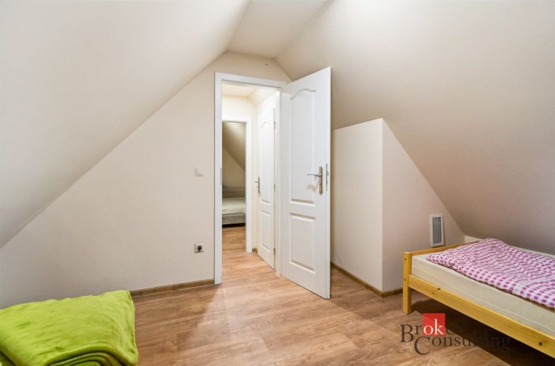 A room in a cottage with a wooden decor floor and a single bed.