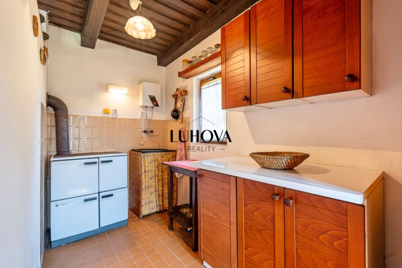 A kitchen in a cottage with a wooden cabinet and a stove, floor with brown decor.