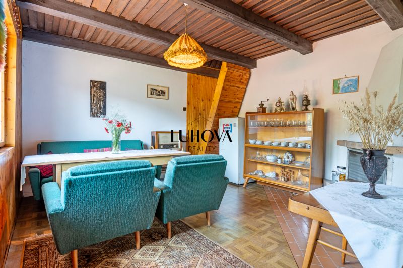 The interior of a cabin with green armchairs, a dining table, and a cabinet with dishes.