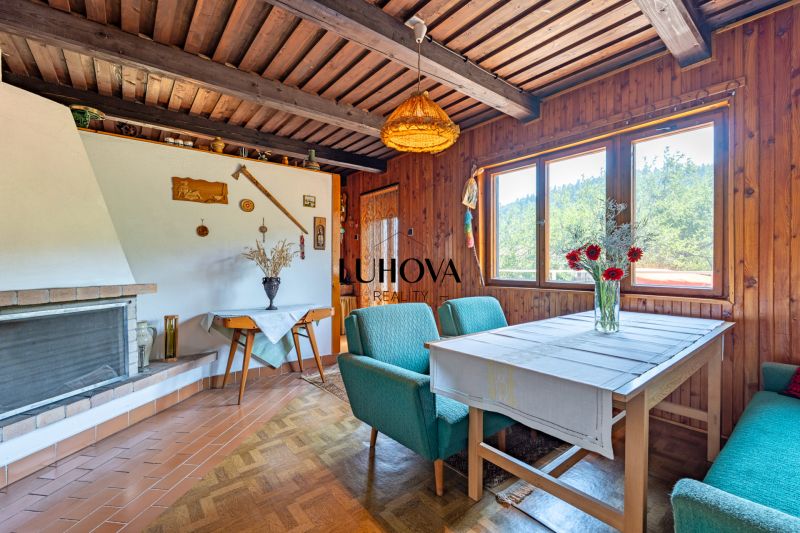 The interior of the cabin with wooden decor, a fireplace, and flowers on the table feels cozy.