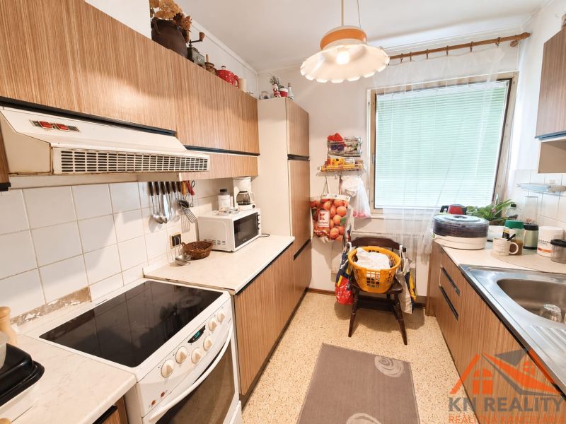 The kitchen in the family house has simple furniture with a wooden decor and white appliances.