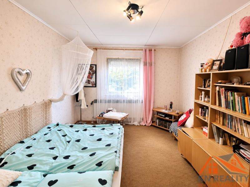 Room of a family house with a bed, bookshelf, and colorful accessories.