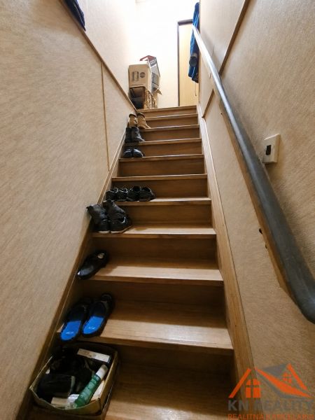 A staircase with a wooden decor floor full of shoes in a family house.