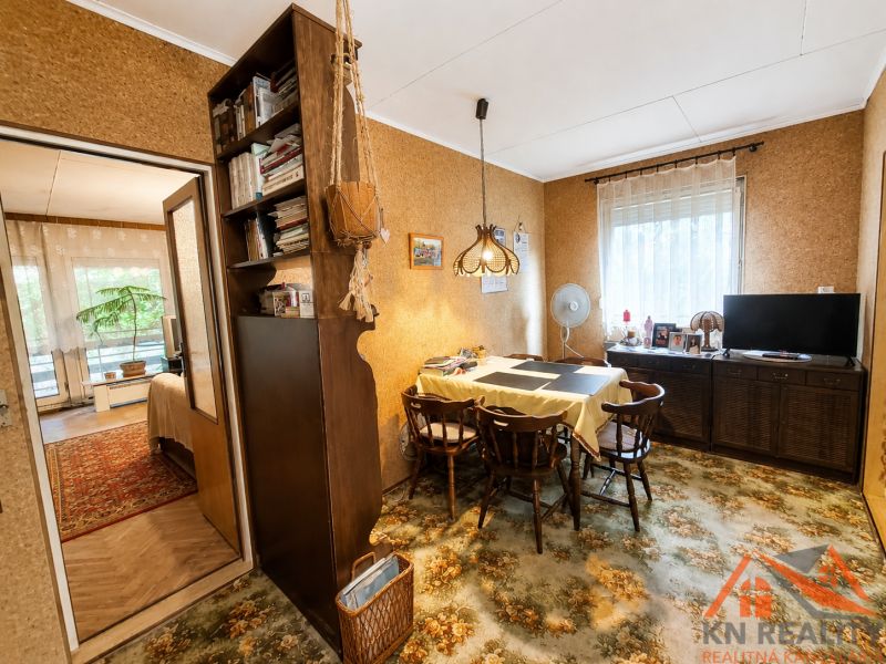 A dining room in a family house with wooden decor on the floor and a carpet with a floral pattern.
