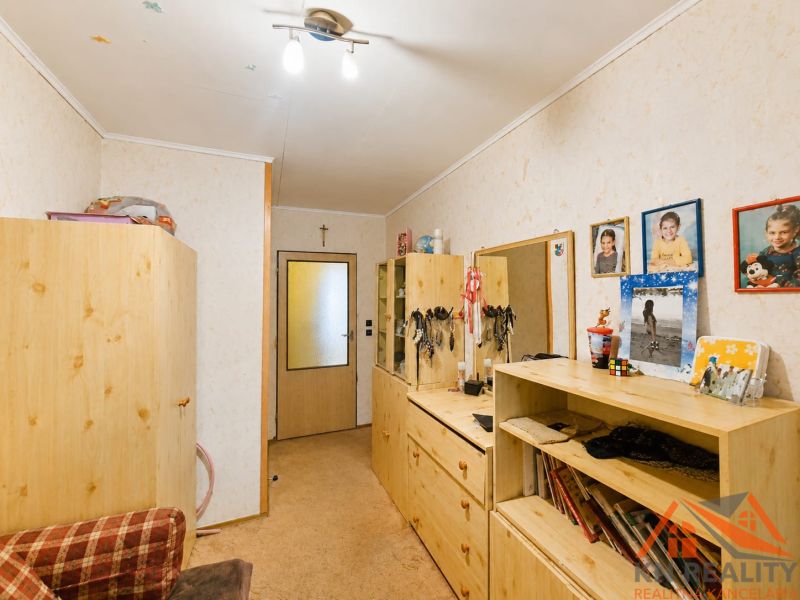 Interior of a family house with wooden furniture, a carpet, and photographs on the wall.