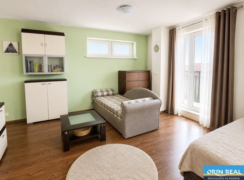A room in a one-room apartment with a sofa, furniture, and a wooden decor floor.
