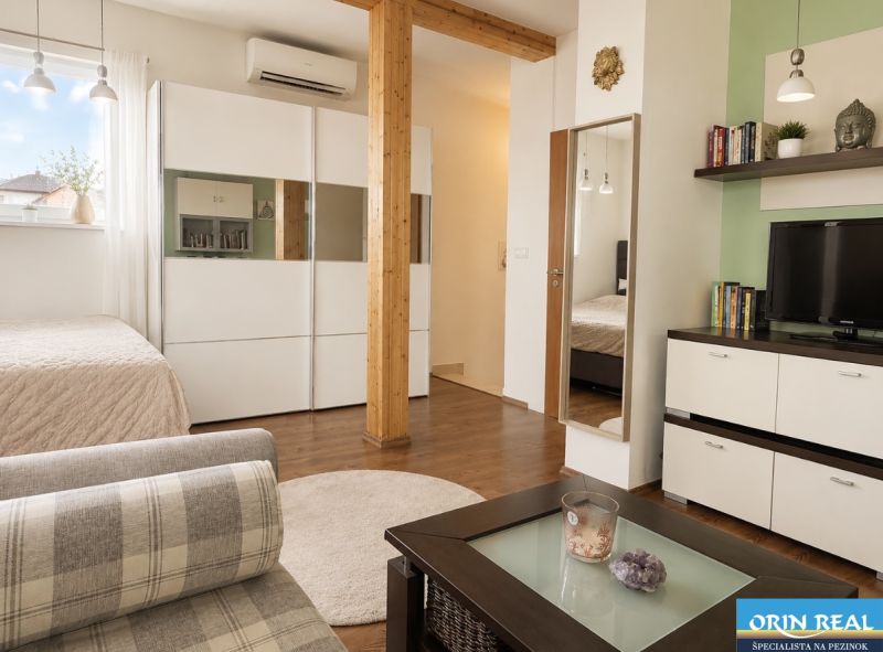 Living space in a one-room apartment with a wood-patterned floor and modern furniture.