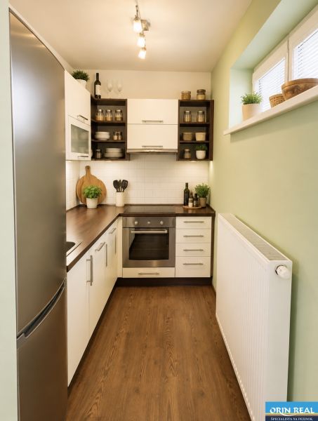 A kitchen in a studio apartment with a wooden decor floor and built-in appliances.