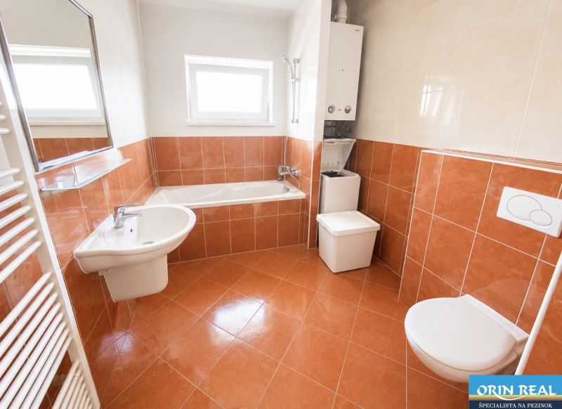 A bathroom with a bathtub, sink, toilet, and washing machine in a studio apartment.