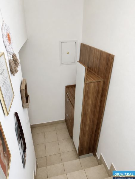 A staircase with storage space in a studio apartment, white wall, wooden decor.