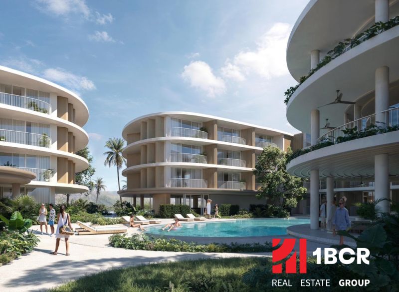 Apartment construction in Surat Thani with rounded buildings and a pool in the middle of the complex.