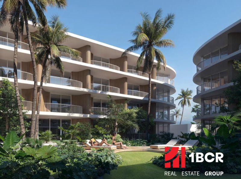 Apartment buildings in Surat Thani: apartment buildings with palm trees and greenery in the background.