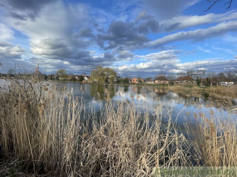 A lake and family houses in Tvrdošovce surrounded by natural scenery and sky.