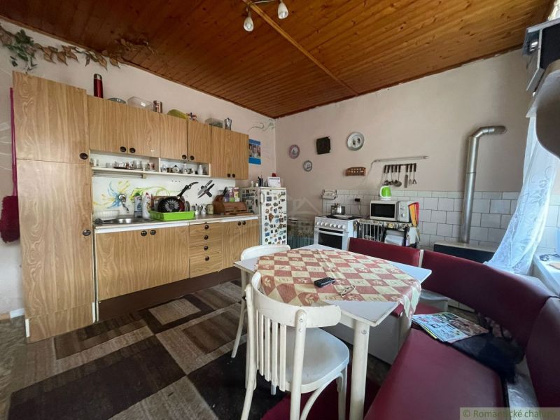 A kitchen in a family house with a wooden decor, a dining table with chairs and a couch.