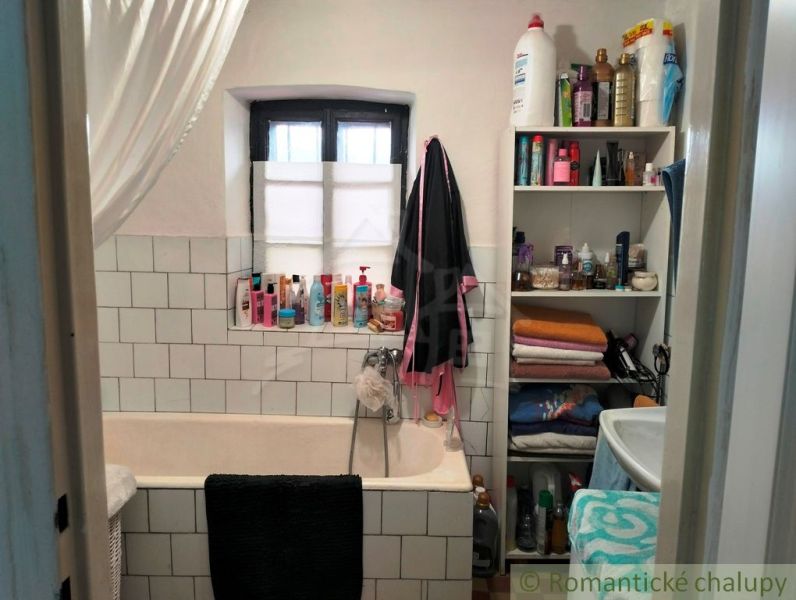 Bathroom in a family house with a bathtub, shelves, and various toiletries.