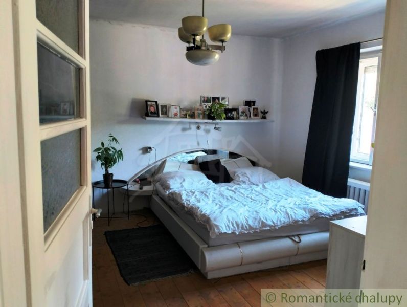 Bedroom with a double bed, plant, and wooden decor flooring in a family house.