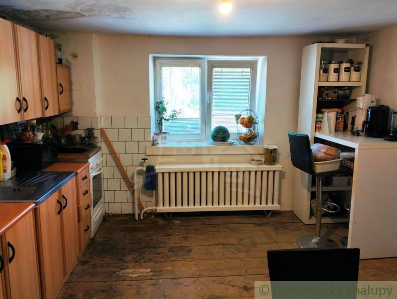 A kitchen in a family house with a wooden decor floor, equipped with appliances and furniture.