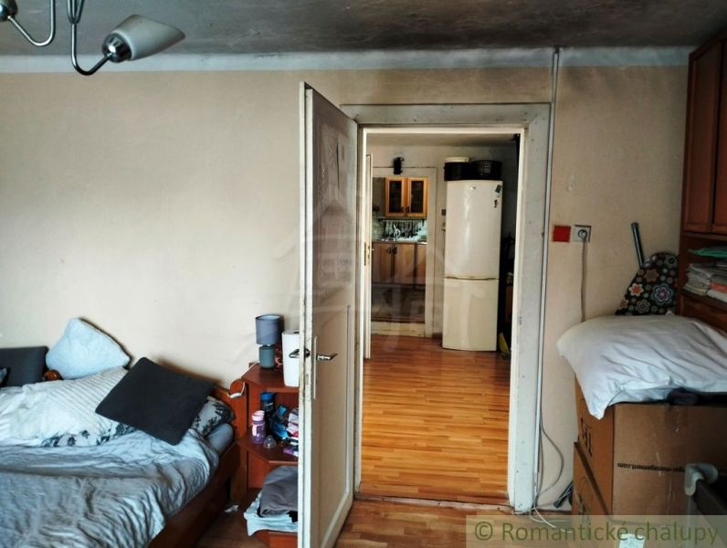 The interior of a family house with a bed and a view of the kitchen through open doors.