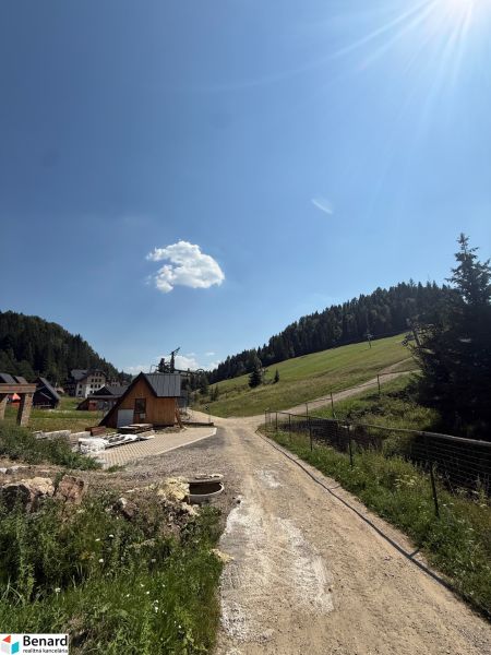 Recreational plots in Litmanová with a scenery of forest and houses, blue sky.