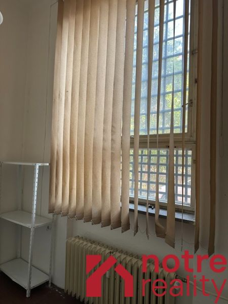 Offices with vertical blinds and a shelving unit, floor with wood decor.