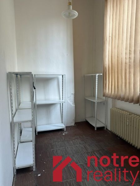 Office with shelves, a radiator, and curtains, floor with wood decor.