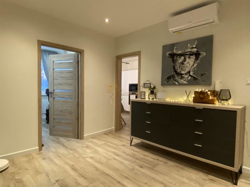 Interior of a 3-room apartment with a dresser, a portrait on the wall, and a floor with a wooden decor.