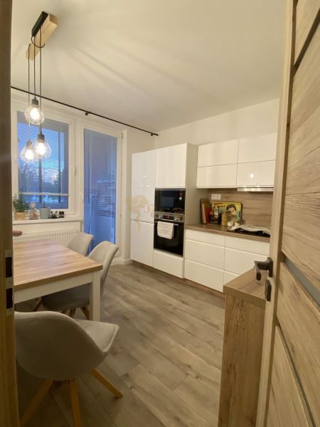 A kitchen in a 3-room apartment with a wooden decor floor and a dining table.