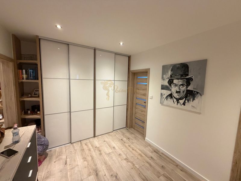 A room in a 3-room apartment with a wooden decor floor and a picture on the wall.